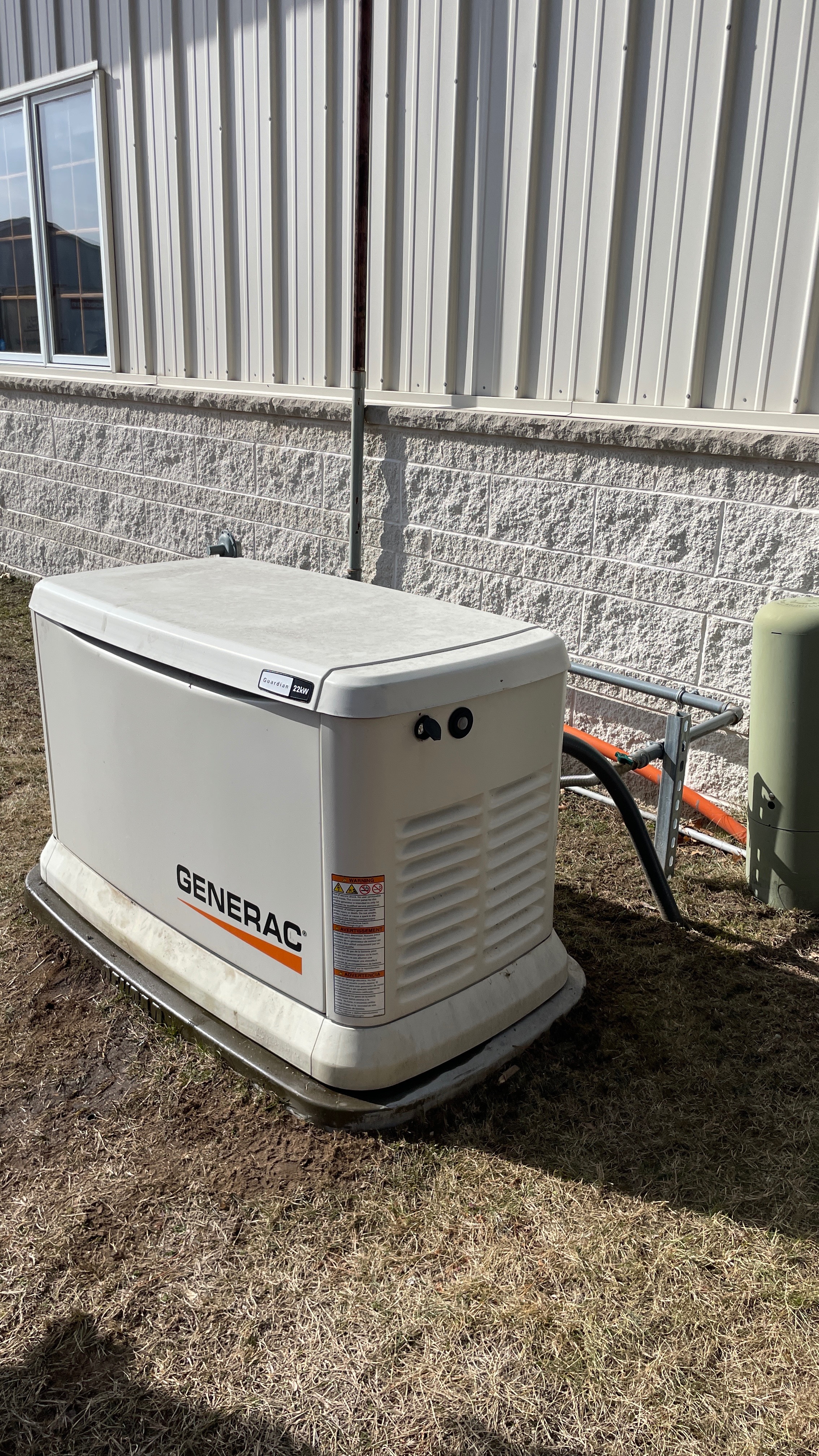 Generac Guardian standby generator installed beside a commercial metal building
